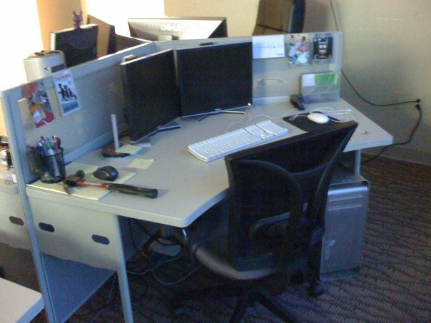 A startup desk, complete with chair, monitor, keyboard, and... a hammer?