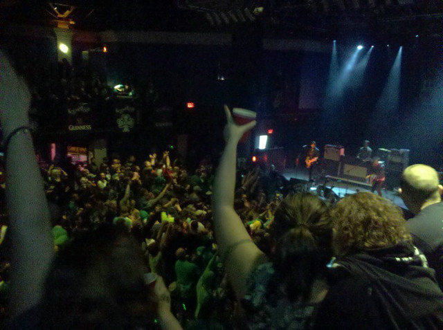 A venue packed full of drunk people. Looking down onto the stage, where a band is playing.