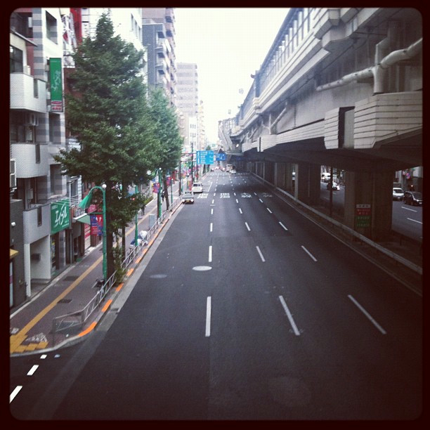 A view of a street in Tokyo. A highway pass runs overhead.