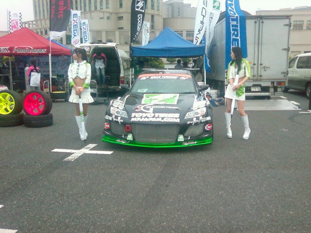 A drift car flanked by two women.