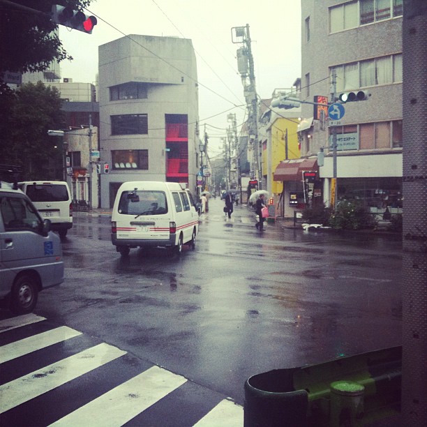 A rainy intersection in Tokyo. Cars are navigating traffic.