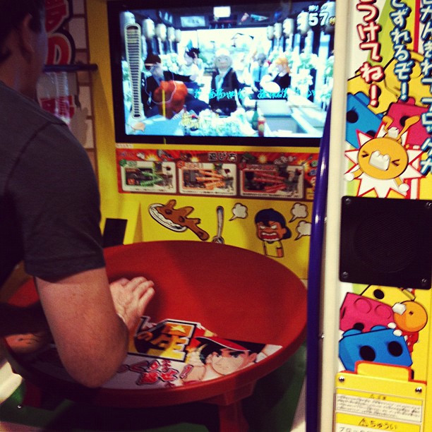 A man is playing an arcade game where you simulate flipping a table.