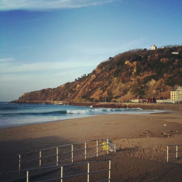 A view from the top of a walkway down to a beach area. A large hill in the distance.