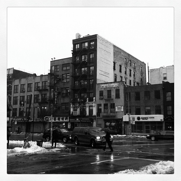 A street in Chinatown, NYC. A person is crossing in the crosswalk.