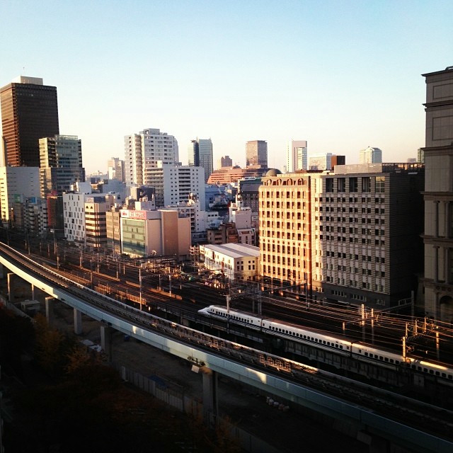 A top-down view of Tokyo. Nestled between buildings, a bullet train is running.