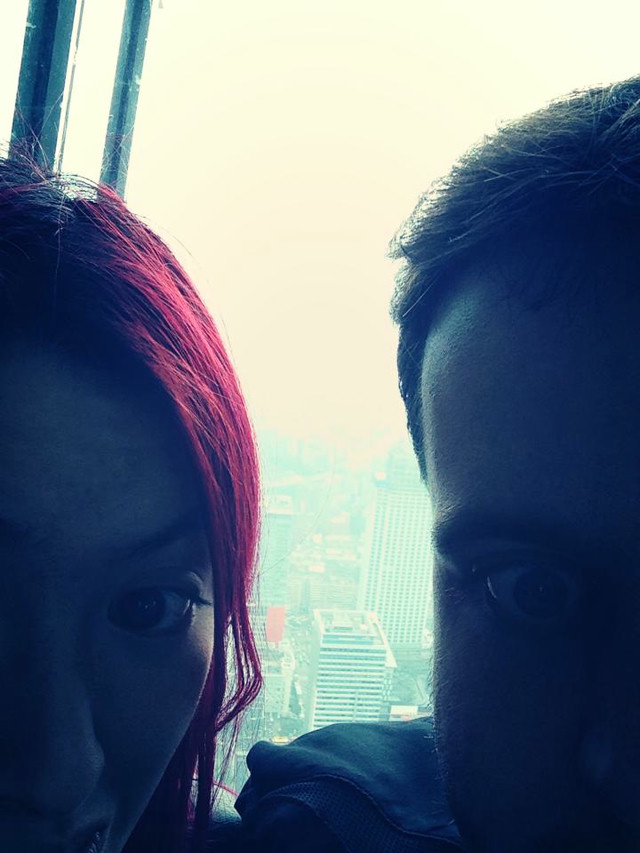 A selfie of girlfriend and myself. She has pink hair. The landscape of Taipei is barely visible in the background.