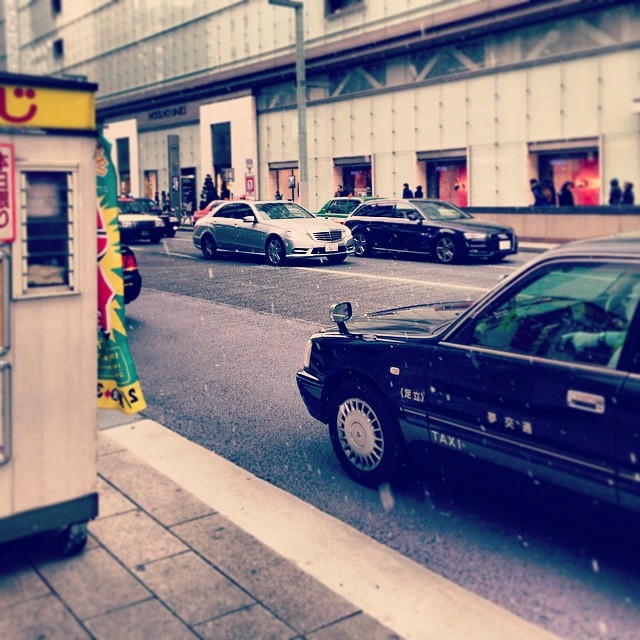 A taxi cab drives by in Ginza, with a light dusting of snow in the frame.