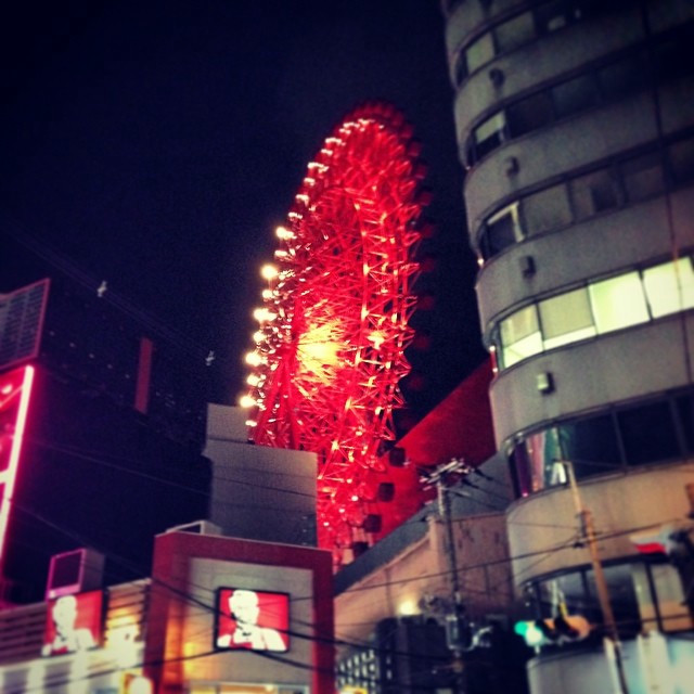 A bright red ferris wheel on top of a building.