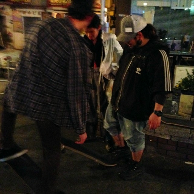 A couple people flipping a skateboard in the middle of the sidewalk.