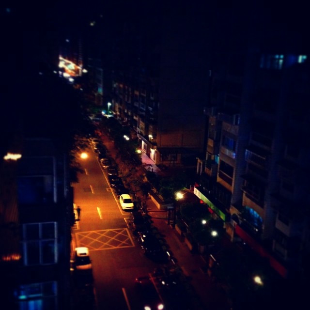 A top-down view of a side street in Taiwan at night. Cars litter the dimly lit street.