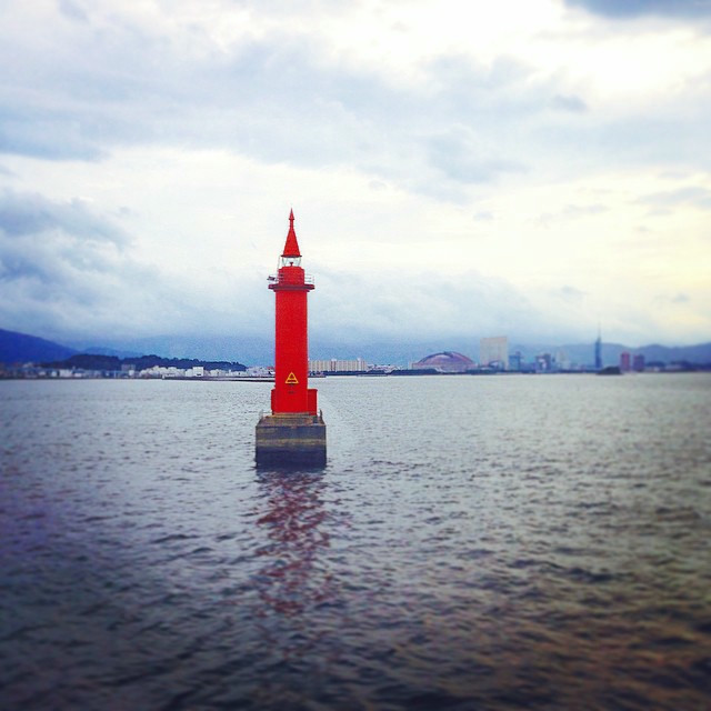 A bright red buoy floating in the water, used to guide ferries near Busan.