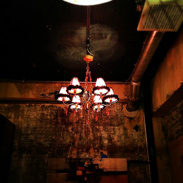 A chandelier hangs from the back of a dimly lit restaurant.