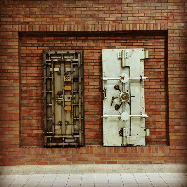 Two old bank vault doors mounted on a brick wall.