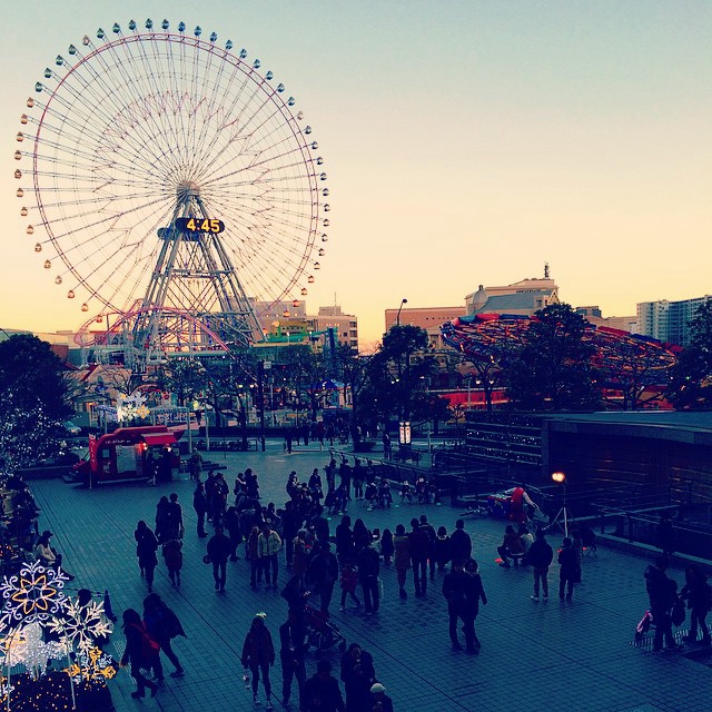 A photo of central Yokohama. People are milling about, and carnival attractions - like a ferris wheel - are in the background.