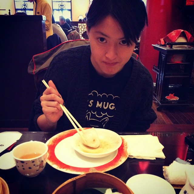 A woman holding chopsticks, about to eat a dumpling. In a Chinese restaurant.