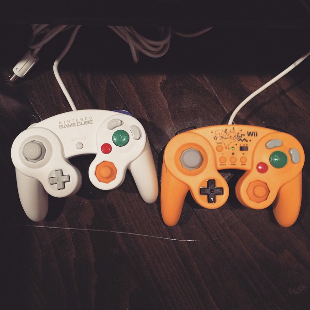 A white Gamecube controller next to a yellow Gamecube controller.