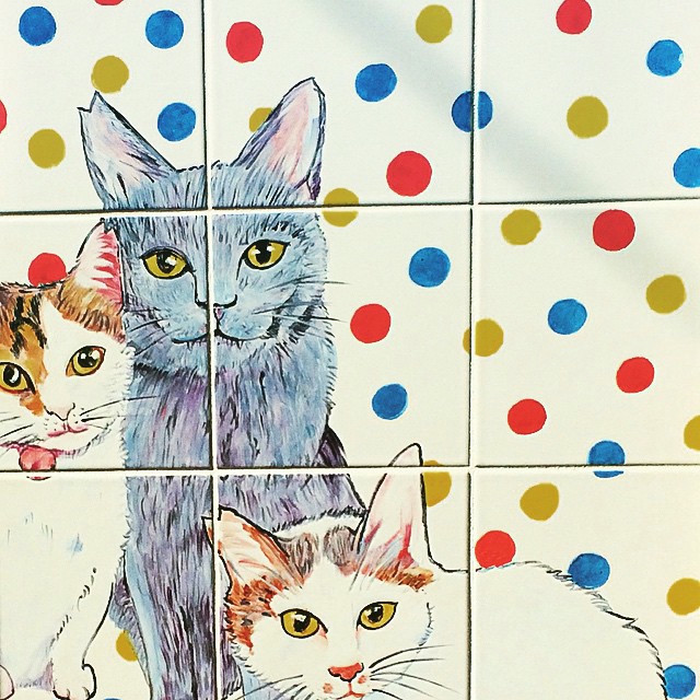 Artwork of cats on a wall, with polka dot pattern adorning.