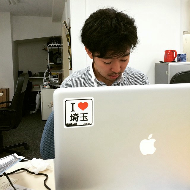 A man at his laptop, now adorned with an i-heart-saitama sticker.