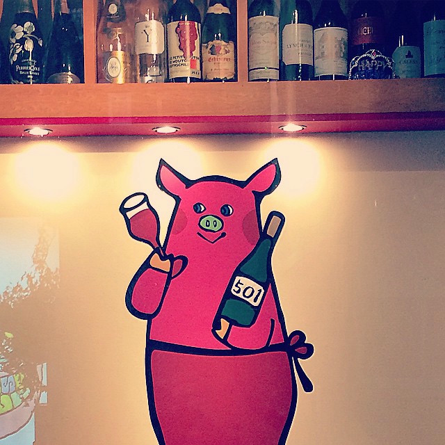 A pink cartoon pig holding wine.