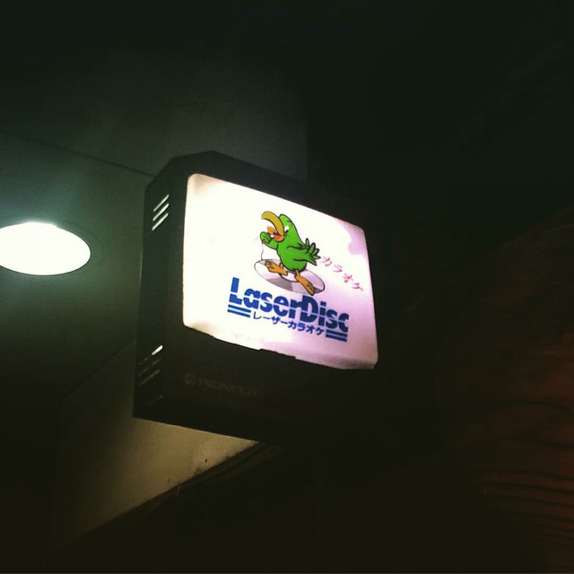 A bar sign that says 'laserdisc'. A green cartoon bird features.