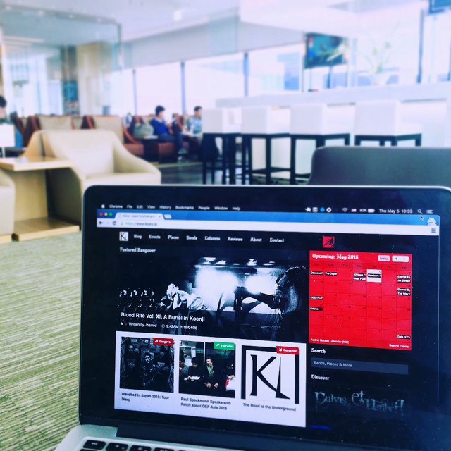 Looking out into an airline lounge. A metal magazine website is displayed on a laptop on the table.