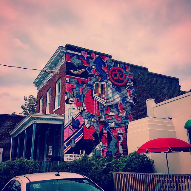 Artwork on the side of a brick townhome building in Richmond VA. Various red and blues, themed with a 90s internet motif.