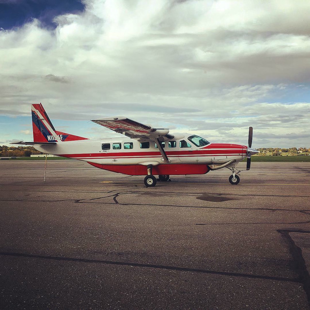 A red and white small prop plane on a runway at Dulles airport, VA.