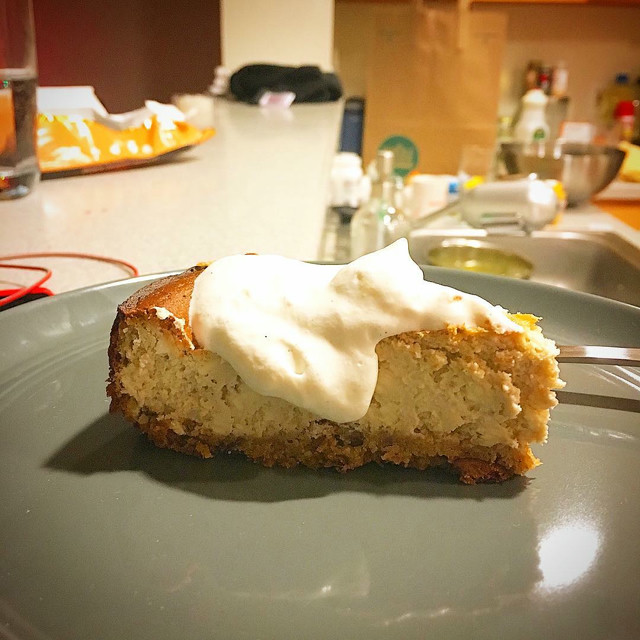 A slice of homemade cheesecake with whipped cream on top.