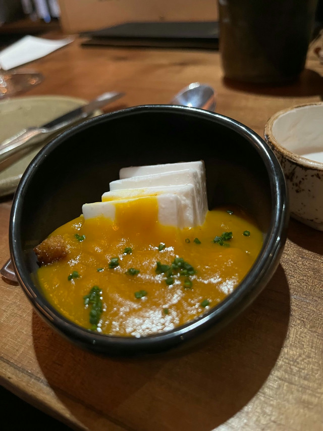 A small black bowl filled with slices of tofu and a miso green onion sauce.