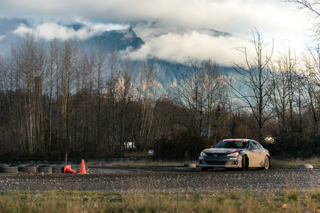 A car slides out of the woods at high speed. Above, the blue mountains of Snoqualmie are on display.