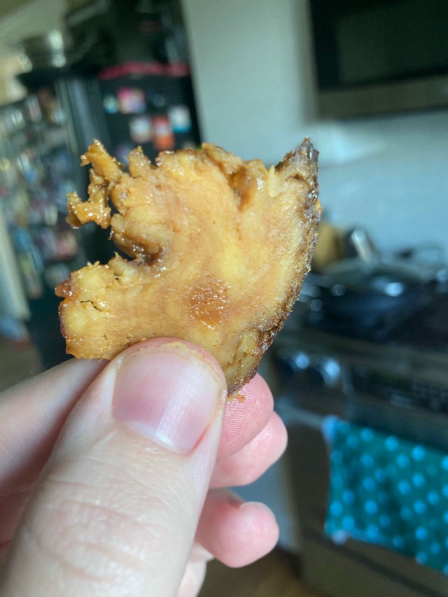 A cross-shot of a slice of vegan seitan brisket. There's a visible fatty deposit that's caused by peach tree sap. The brisket is brown and marbled with different layers, and there's a crust exterior due to the cooking process.