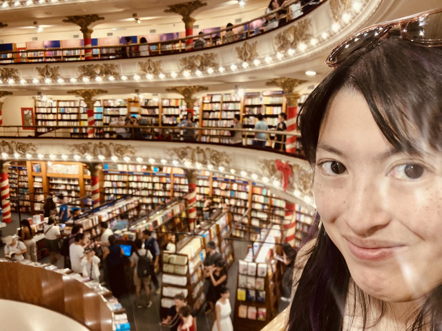 A woman smiling in front of a bookstore