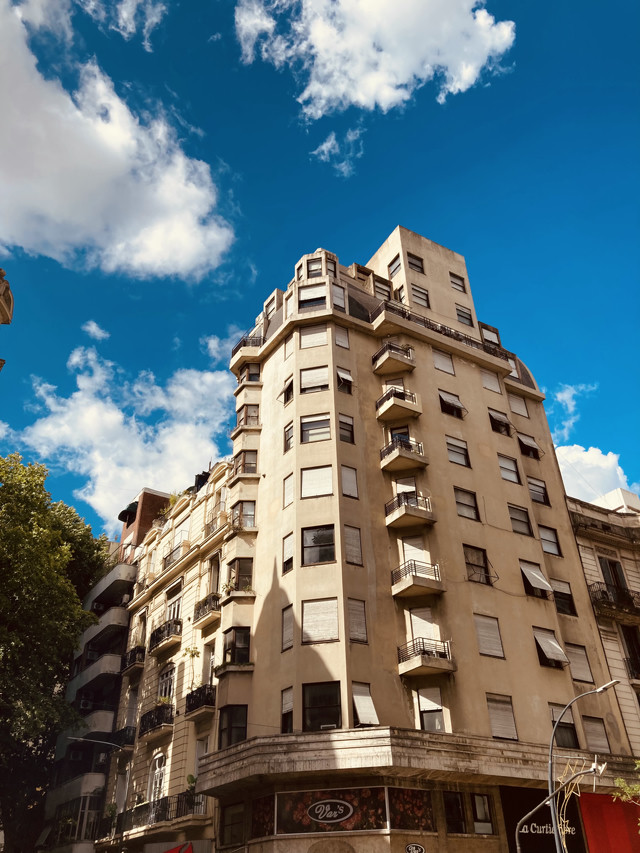 A yellowed building in downtown Buenos Aires, Argentina. The building contains apartments. The blue sky is visible above.