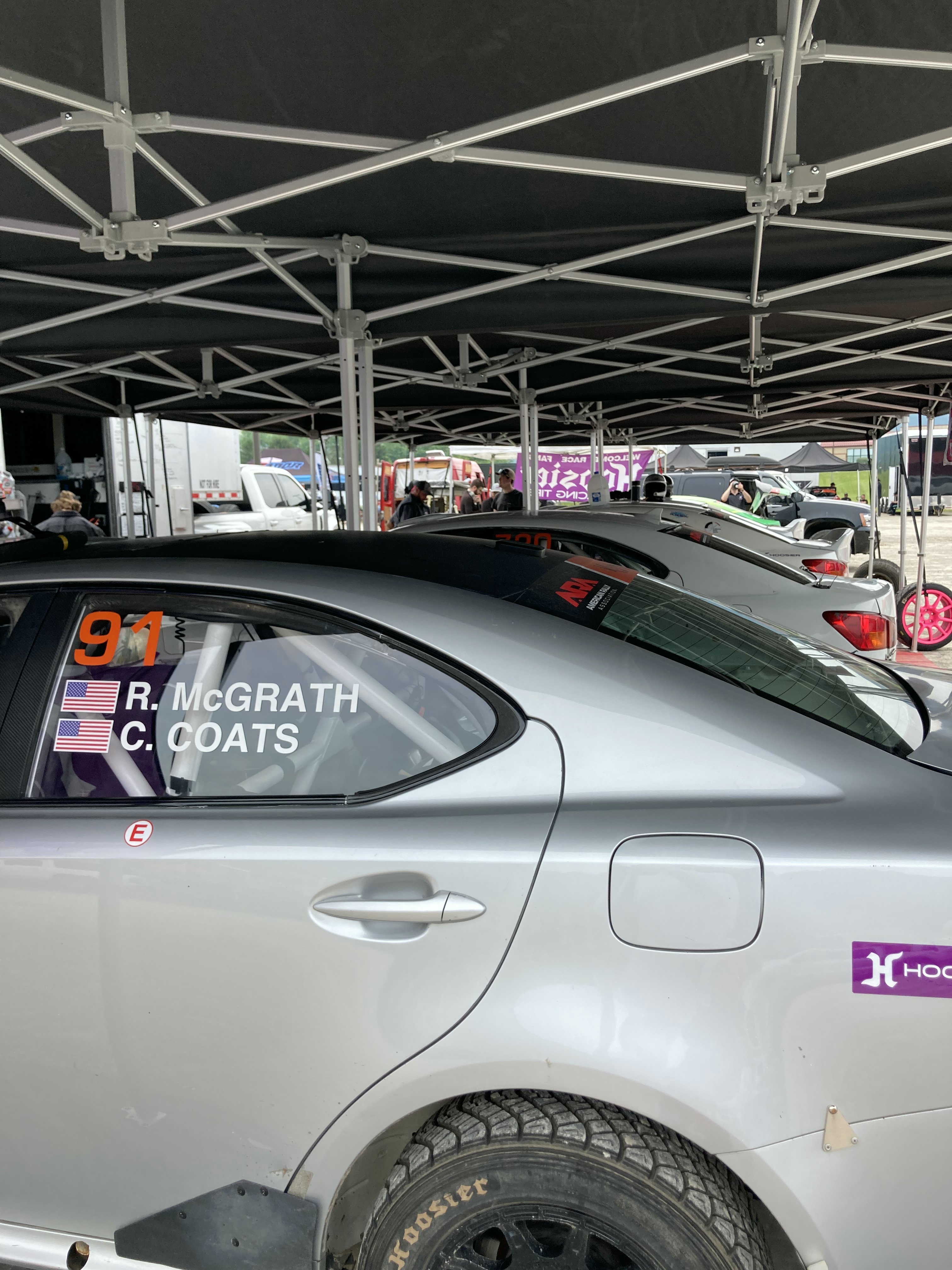 A lineup of rally cars under a tent.