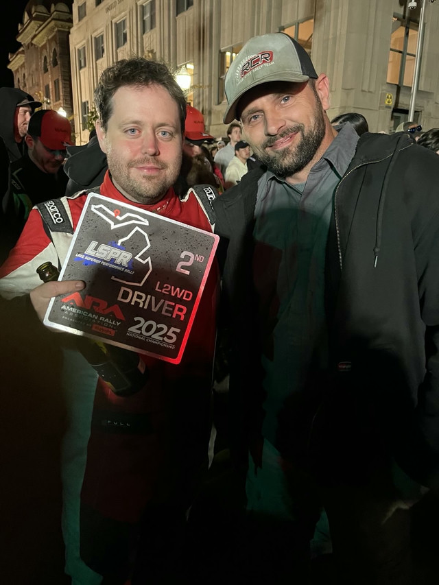 Me standing exhausted after finishing a race. I’m holding a black trophy for 2nd place. My mechanic stands next to me.