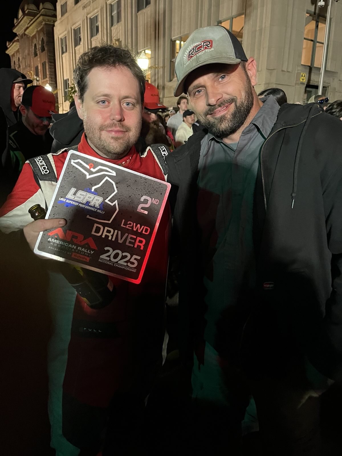 Me standing exhausted after finishing a race. I’m holding a black trophy for 2nd place. My mechanic stands next to me.