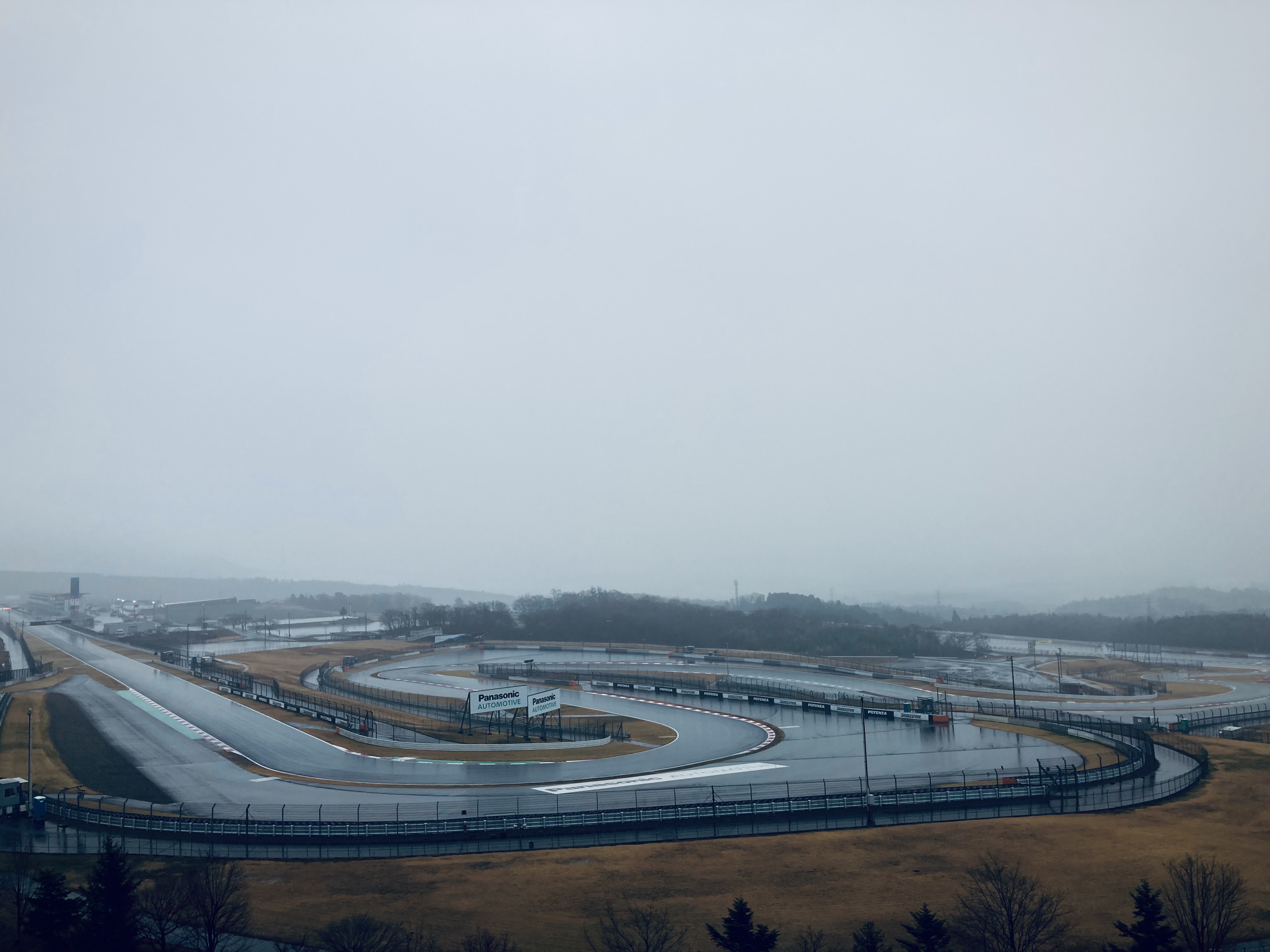 A very wet and rainy Fuji Speedway. The sky is gray and overcast.