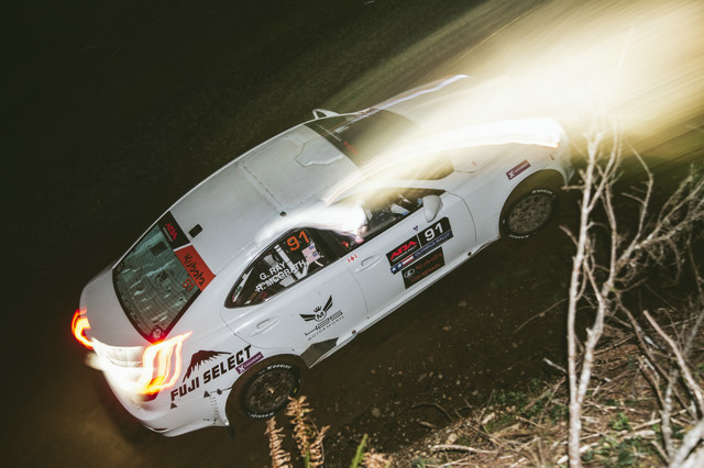 A white Lexus IS250 racing through the night. The lights in the photo shift under movement.