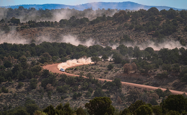 A white Lexus IS250 streaks through the high desert of Colorado. Massive dust clouds can be seen in its wake.