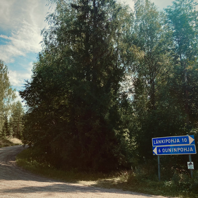 A blue sign points left towards a legendary rally road.
