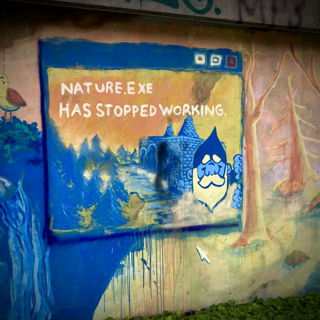 A Windows XP styled street art that states nature dot exe has stopped working. A gnome and crumbling remains can be seen on it.