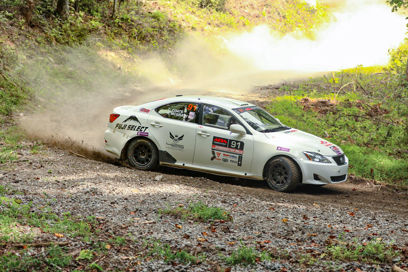 A white Lexus IS250 slides through a turn in the woods.