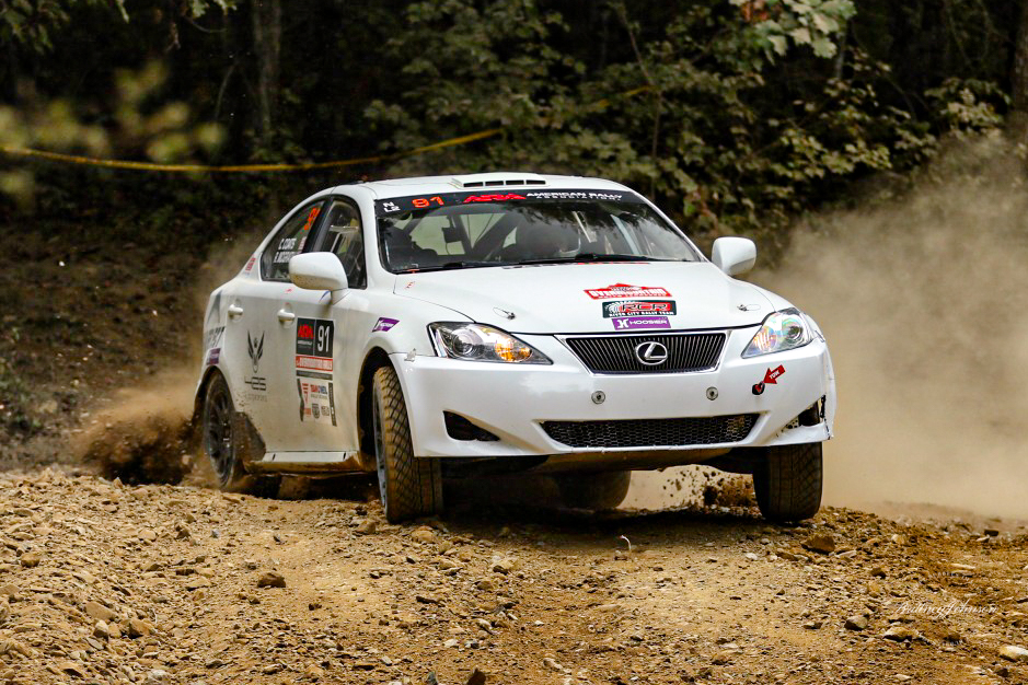 A white Lexus IS250 chewing through a beat up dirt road.