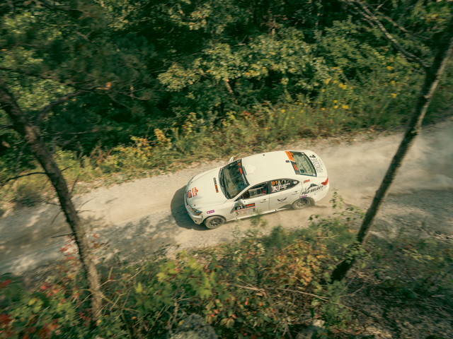 A white Lexus IS250 racing through the woods, view from the top down.